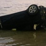 Car lands in water after light pole smash