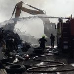 Fire crews work on deep-seated fires amid scrap metal